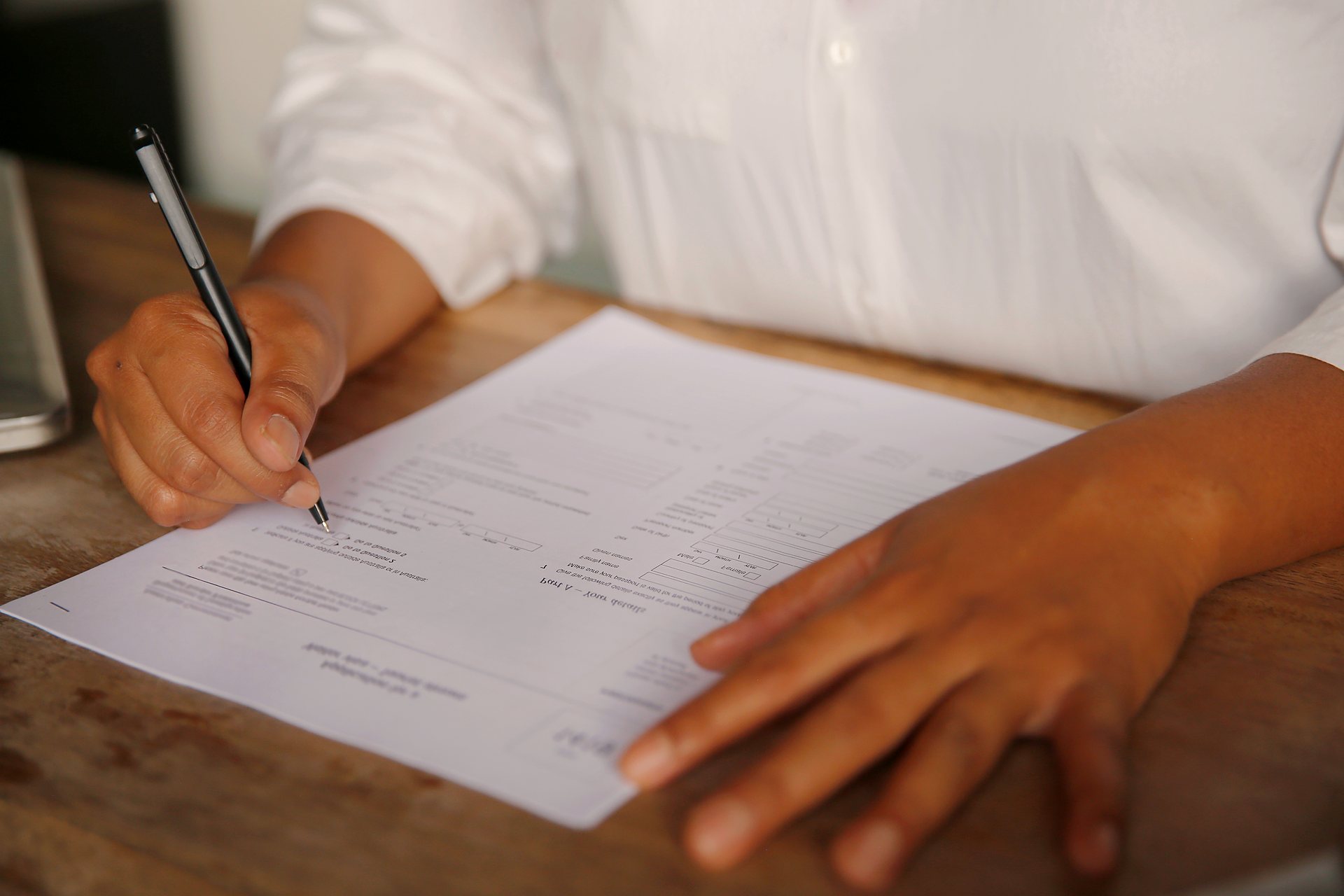 Hands filling in an official application form at a desk