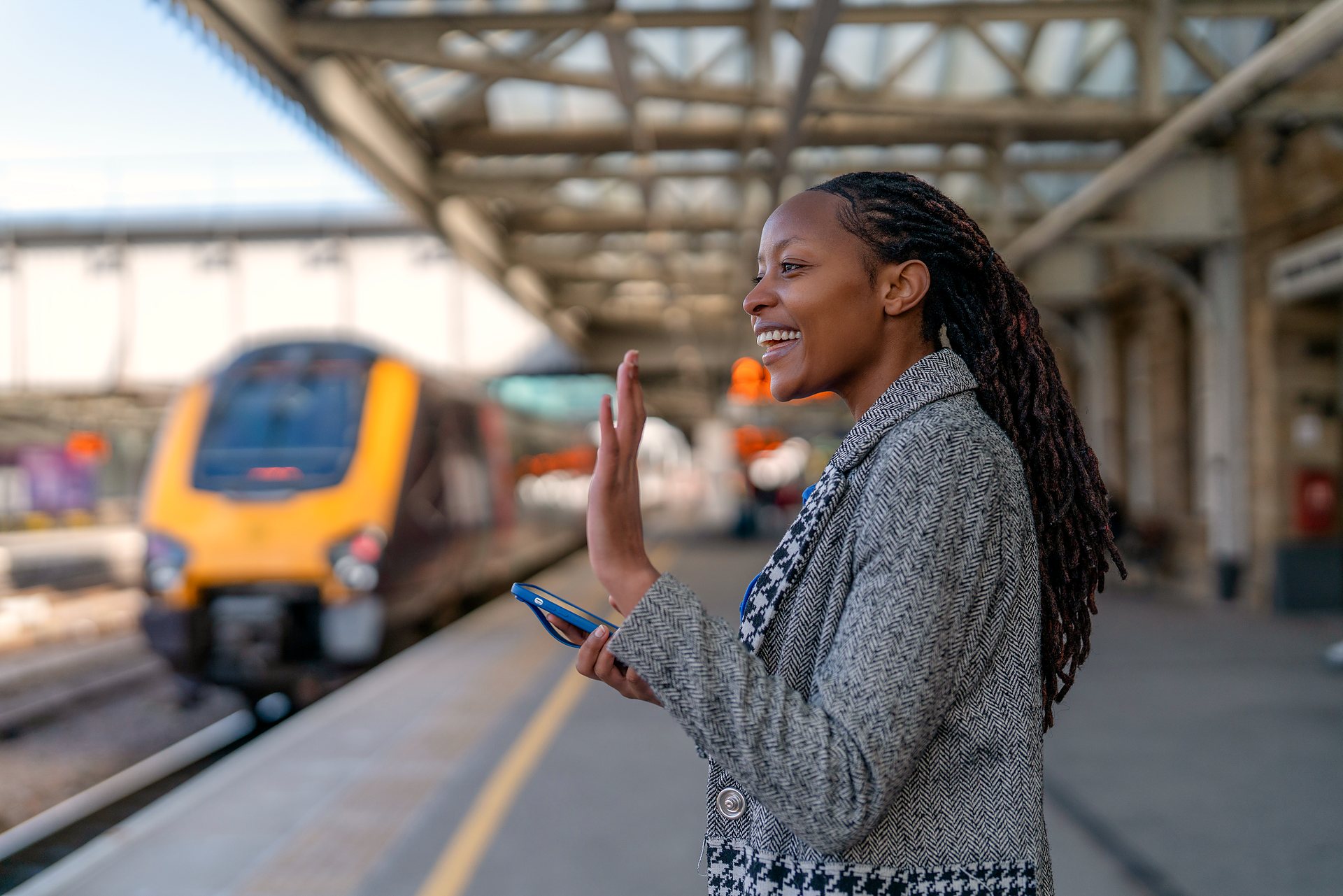 A traveller waving as her train arrives at the platform