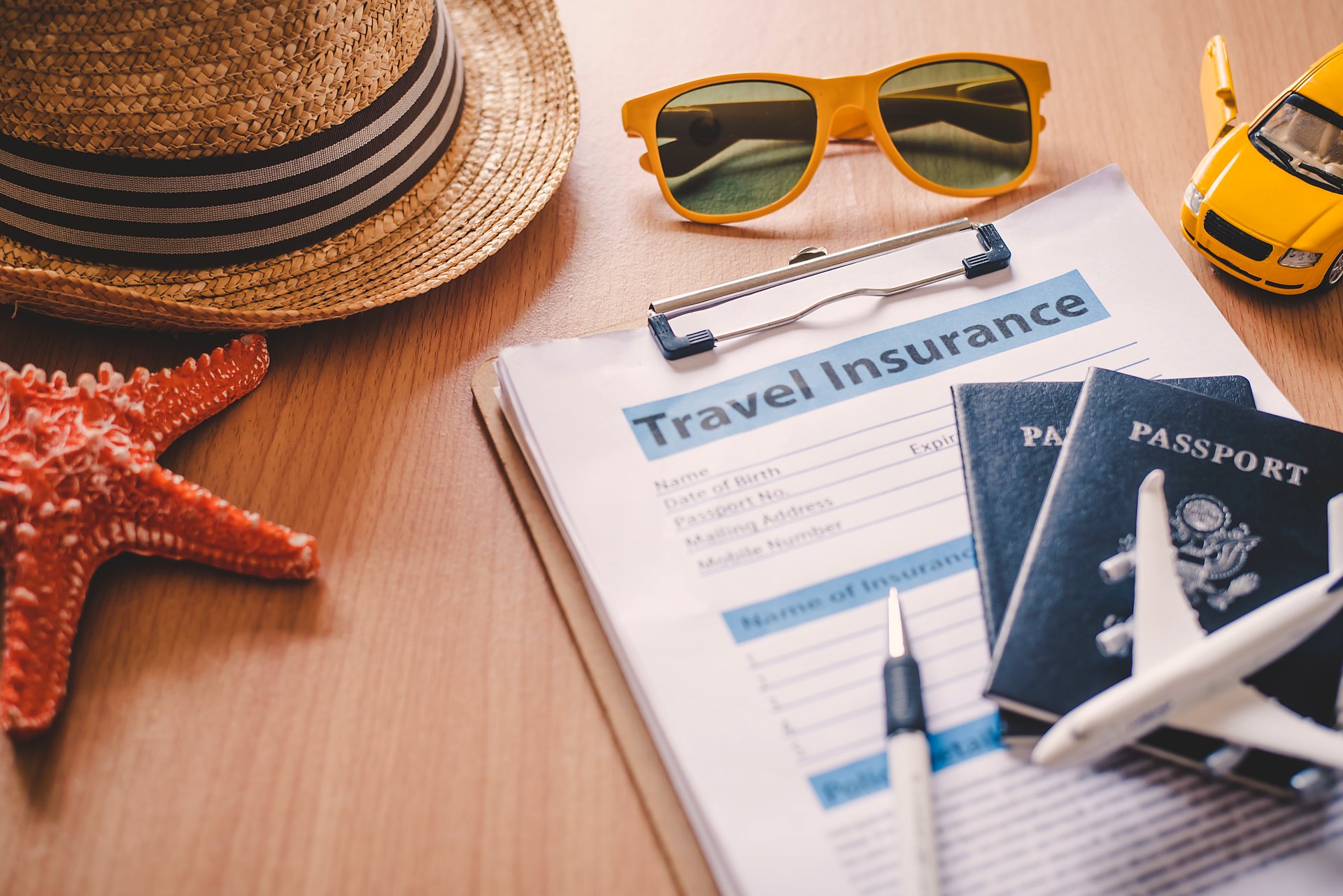 Passports, travel insurance forms and holiday accessories on a desk